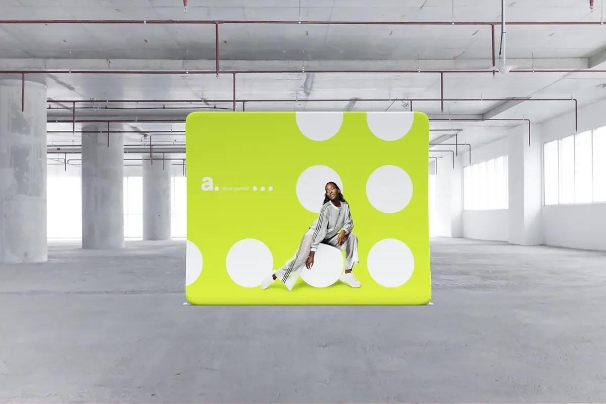 Nowoczesna ścianka reklamowa z tkaniny z nadrukiem &mdash; kobieta w modnej stylizacji na tle zielono-białych groch&oacute;w w industrialnym wnętrzu.